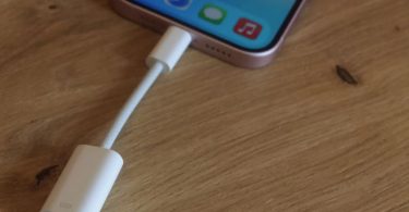 Adaptateur USB-C vers Lightning Apple posé sur un bureau moderne avec smartphone.