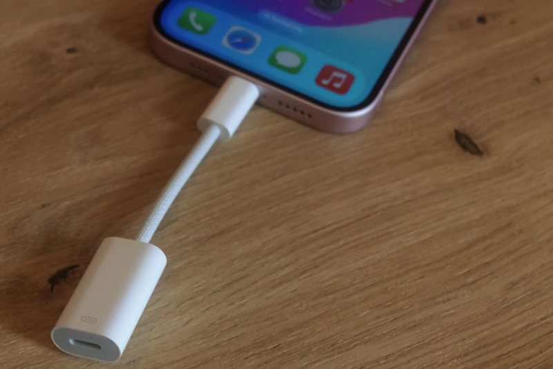 Adaptateur USB-C vers Lightning Apple posé sur un bureau moderne avec smartphone.