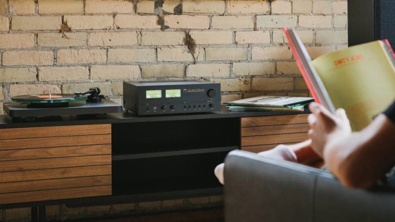 L’amplificateur NAD C 3030 au design néo-rétro, installé dans un système Hi-Fi avec platine vinyle et VU-mètres analogiques.