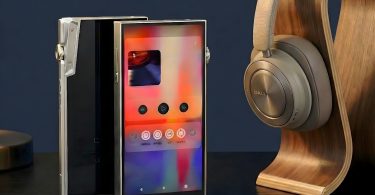 Deux baladeurs audiophiles iBasso DX340 en finition titane posés sur un bureau sombre à côté d'un casque audio DALI sur un support en bois, mettant en avant l'écran tactile et le design métallique brossé.