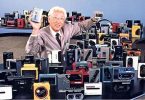 Akio Morita, cofondateur de Sony, souriant au milieu d'une vaste collection de modèles de Walkman vintage, tenant un prototype et un baladeur cassette.