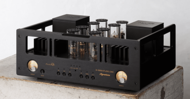 DAC haut de gamme Allnic Audio D-15000 Signature avec châssis noir, tubes apparents protégés par des cylindres en verre et VU-mètres analogiques éclairés.