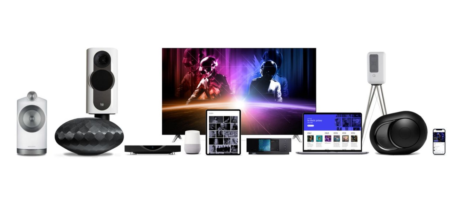 Ensemble d'équipements audio et vidéo compatibles Roon, incluant des enceintes connectées, un téléviseur affichant un concert, une tablette, un ordinateur portable, un smartphone et des lecteurs réseau haut de gamme sur fond blanc.