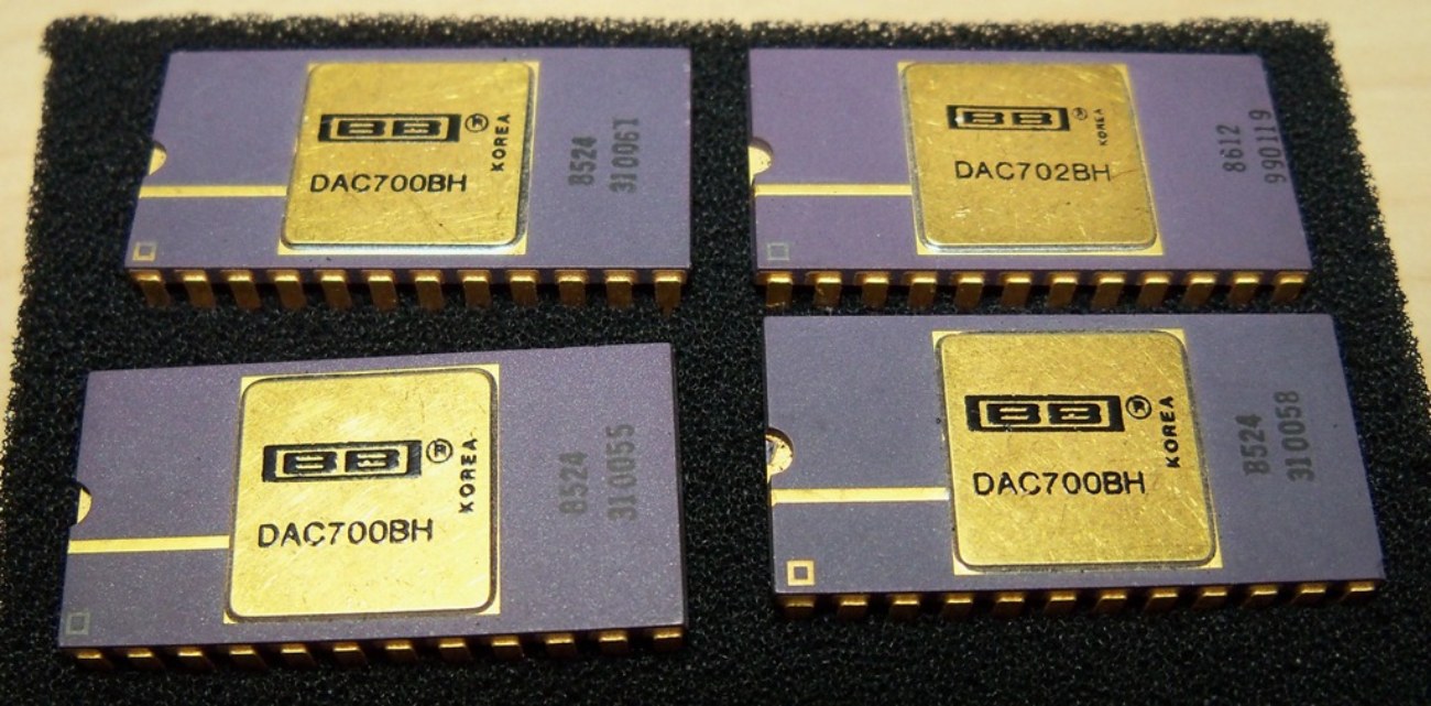 Quatre chips DAC Burr-Brown vintage en boîtier céramique doré : trois DAC700BH et un DAC702BH fabriqués en Corée — des convertisseurs numériques-analogiques de précision industrielle de la première génération, précurseurs des chips DAC audio grand public