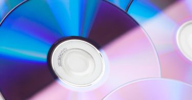 Gros plan détaillé sur des compact discs réfléchissants avec des nuances de bleu et de rose, montrant l'anneau central de données.