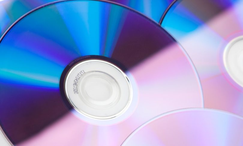 Gros plan détaillé sur des compact discs réfléchissants avec des nuances de bleu et de rose, montrant l'anneau central de données.