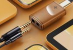 Le dongle DAC FiiO Snowsky Melody en finition bois est posé sur une table avec un casque audio branché, illustrant son utilisation quotidienne.