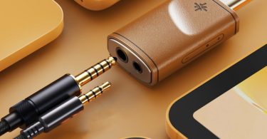 Le dongle DAC FiiO Snowsky Melody en finition bois est posé sur une table avec un casque audio branché, illustrant son utilisation quotidienne.