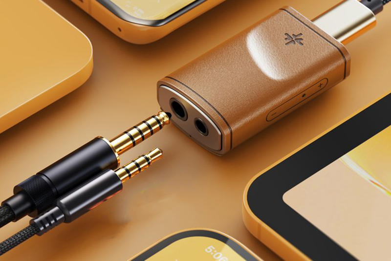Le dongle DAC FiiO Snowsky Melody en finition bois est posé sur une table avec un casque audio branché, illustrant son utilisation quotidienne.