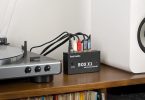 Le préampli phono Fosi Audio BOX X1 est placé dans un environnement intérieur avec une platine vinyle et des enceintes.