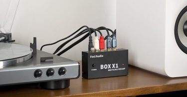 Le préampli phono Fosi Audio BOX X1 est placé dans un environnement intérieur avec une platine vinyle et des enceintes.