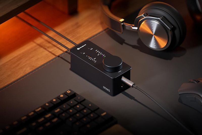 Le Fosi Audio SK02 est posé sur un bureau avec un casque audio branché à proximité