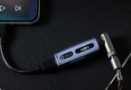 Le HiBy FC3 DAC dongle avec écran OLED posé dans un environnement moderne et lumineux.