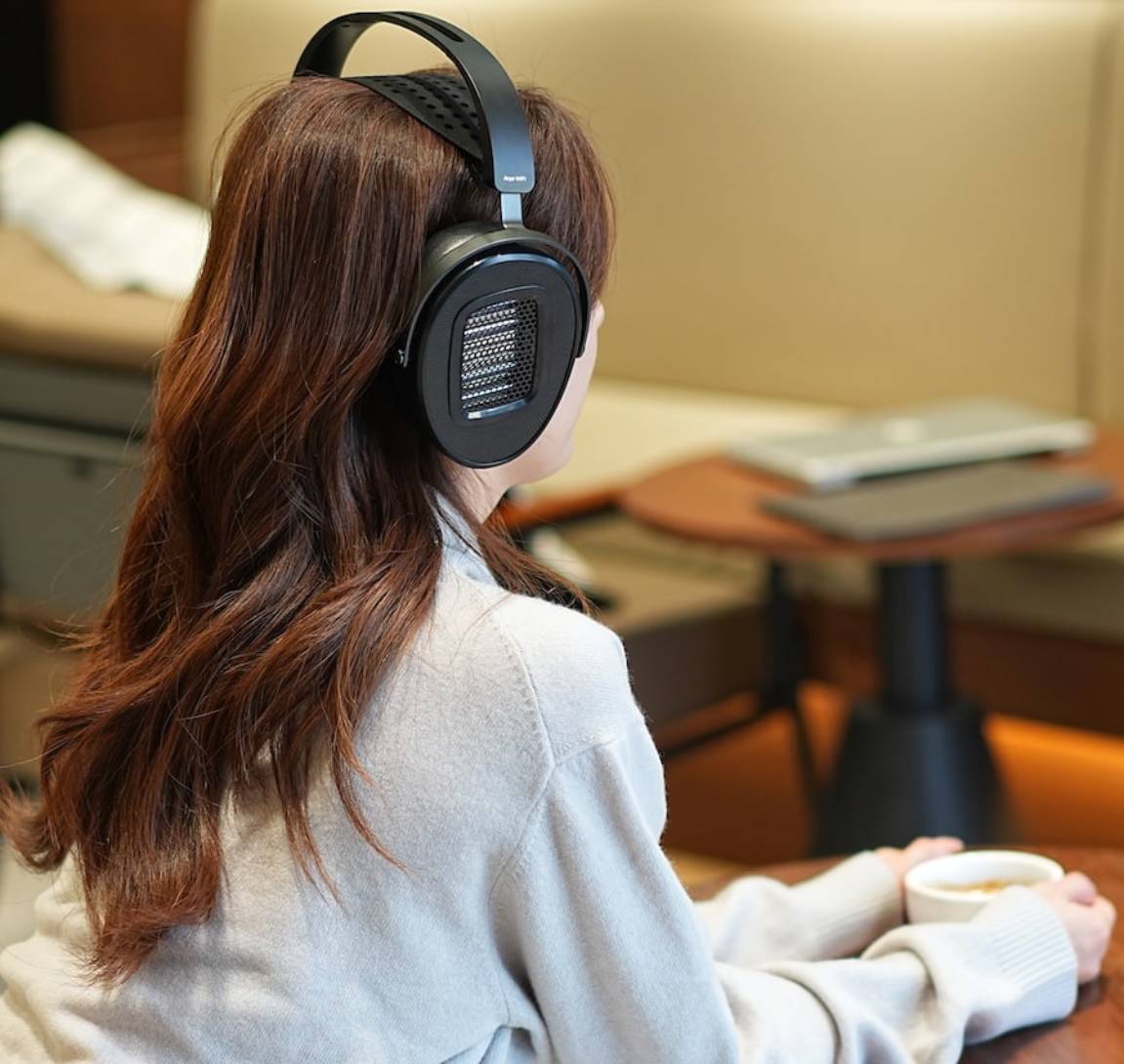 Femme portant le HIFIMAN Arya WiFi en écoute sans fil dans un intérieur cosy 