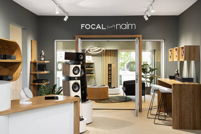 Showroom luxueux exposant des enceintes colonnes Focal Sopra et Utopia avec électronique Naim Audio dans un espace de démonstration moderne.