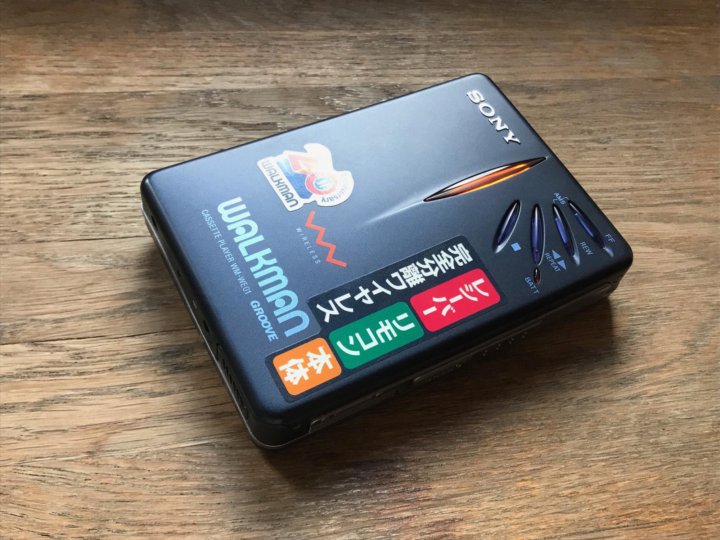 Le Sony Walkman WM-WE01 bleu nuit posé sur une table en bois, arborant le logo du 20e anniversaire et des boutons de commande futuristes.
