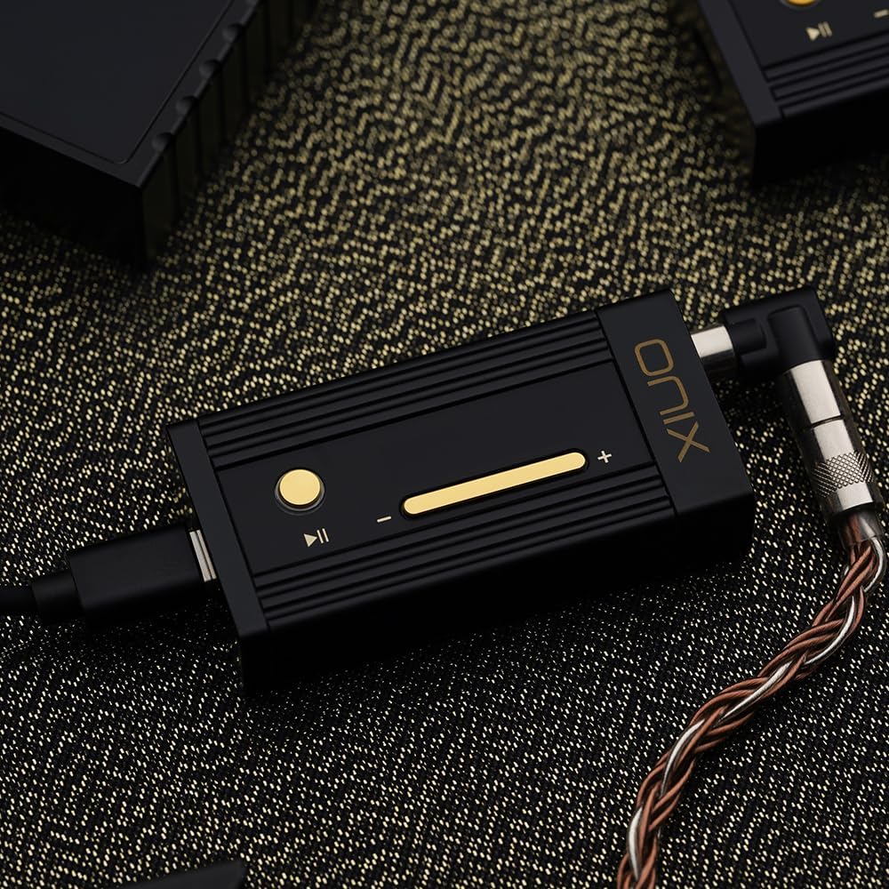 Vue rapprochée du dongle DAC SHANLING Onix Alpha XI1 noir et or avec ses boutons de contrôle physiques et son câble tressé haute fidélité sur un fond texturé.