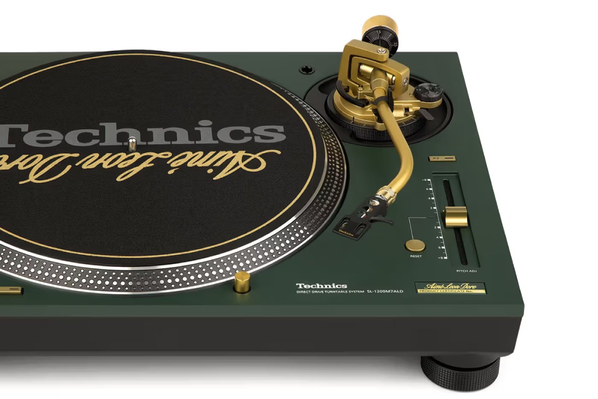 Gros plan sur le bras de lecture en S doré et le curseur de pitch de la platine Technics SL-1200M7ALD, mettant en valeur le contraste avec le châssis Mulberry Green et la plaque de certificat ALD.