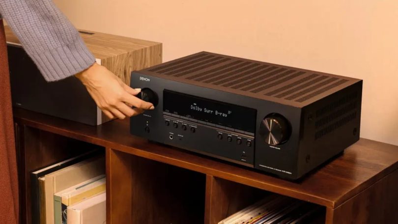 Amplificateur home cinéma Denon AVR-S980H 7.2 canaux posé sur un meuble en bois, avec affichage Dolby Surround Blu-ray