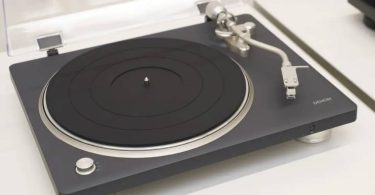 Platine vinyle Denon DP-500BT avec capot plastique transparent ouvert, plateau en caoutchouc noir, bras tangentiel argenté et pieds de découplage chromés