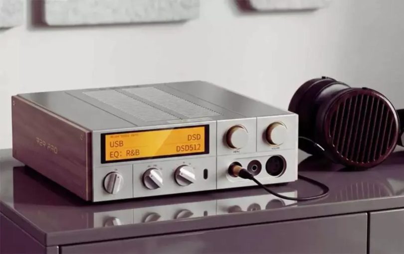 DAC streamer ampli casque FiiO K17 R2R Pro posé sur un meuble laqué prune avec affichage orange montrant USB DSD EQ R&B DSD512, façade argentée avec multiples boutons rotatifs et molette de volume centrale, panneau latéral en bois marqué R2R PRO, présenté avec un casque planar magnétique audiophile
