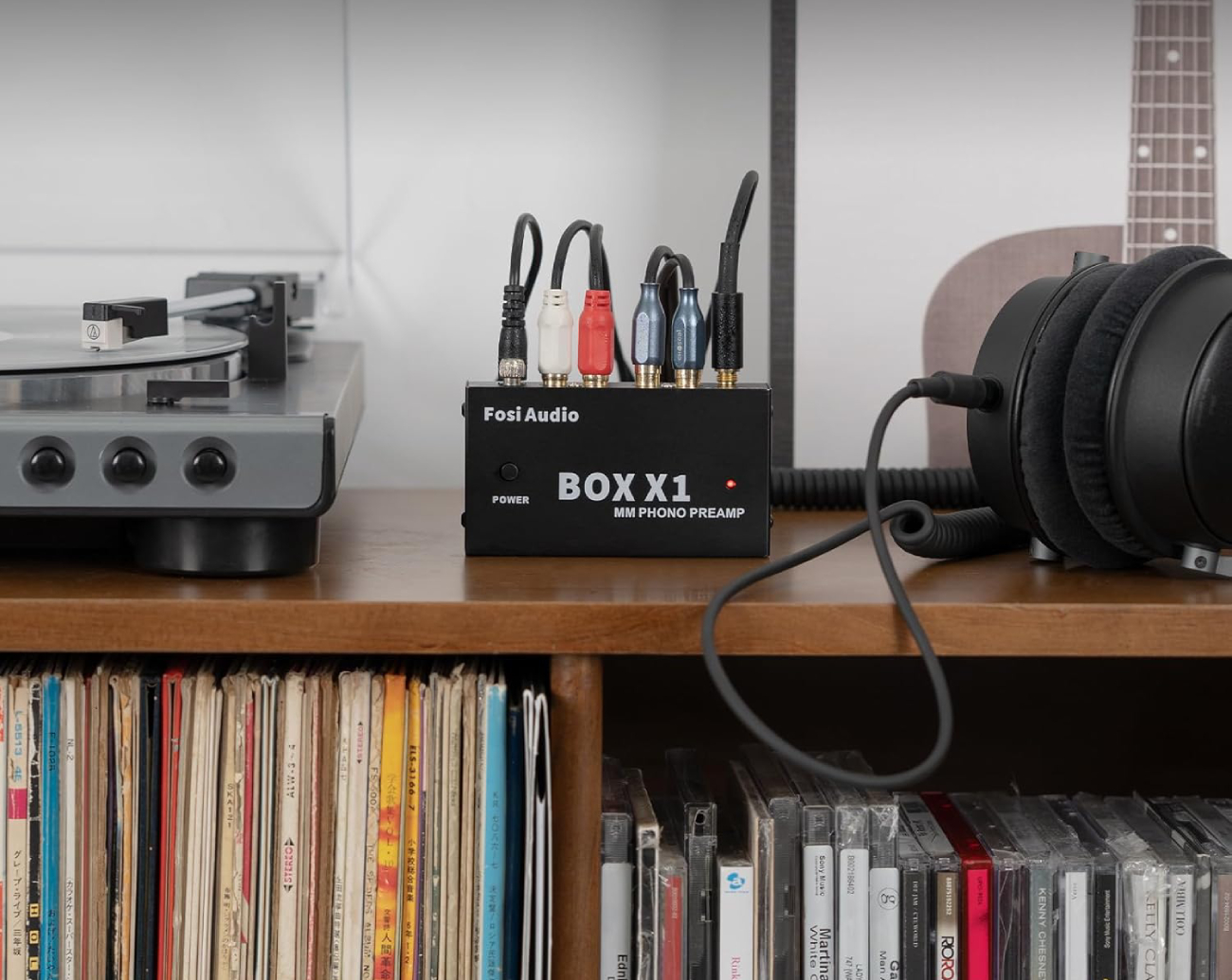 Fosi Audio BOX X1 préampli phono MM connecté à un tourne-disque et casque audio sur meuble avec collection vinyles