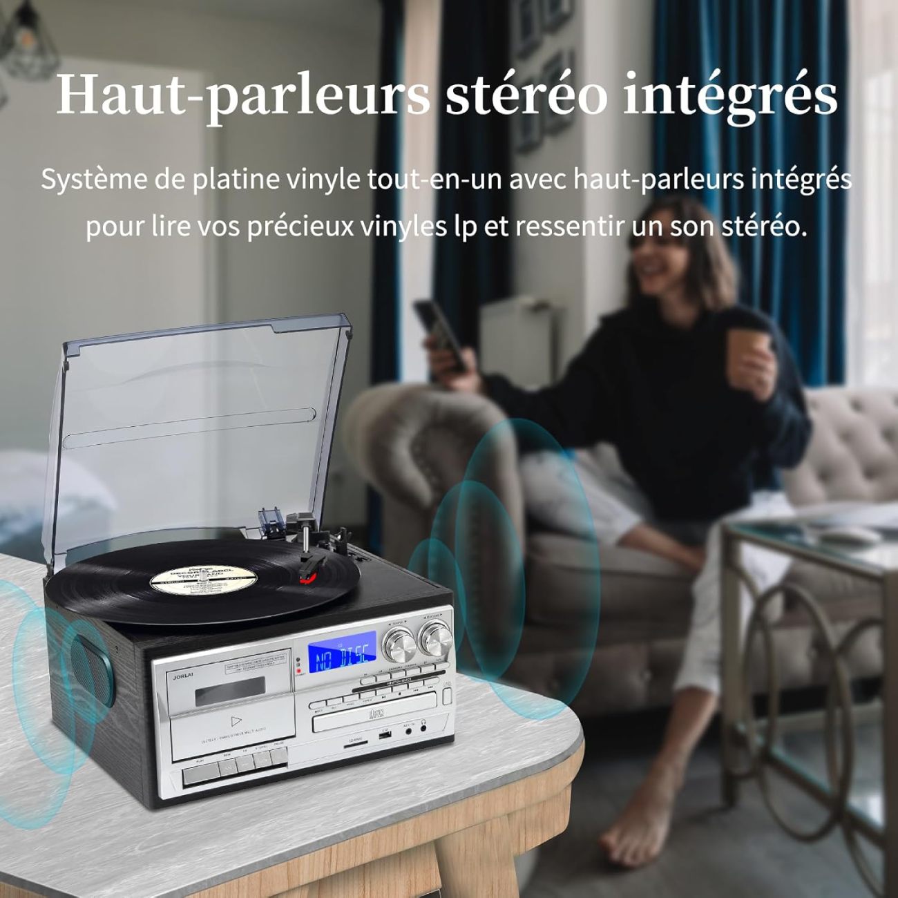 Platine vinyle Jorlau 9-in-1 en situation dans un salon, mettant en évidence ses haut-parleurs stéréo intégrés latéraux et sa façade multifonction (cassette, CD, écran LCD).