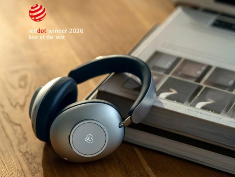 Casque audio Loewe Leo posé sur un livre en bois, avec le badge officiel Red Dot Winner 2026 Best of the Best