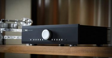 Amplificateur intégré Musical Fidelity M5xi en finition black, vue trois-quarts mettant en évidence le large bouton de volume central argenté, les boutons de sélection des entrées numériques et analogiques, et les ailettes de dissipation thermique latérales du châssis full métal