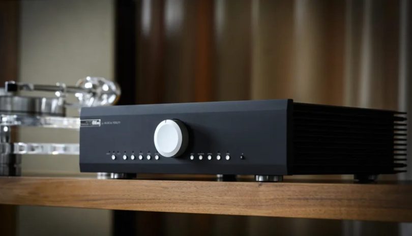 Amplificateur intégré Musical Fidelity M5xi en finition black, vue trois-quarts mettant en évidence le large bouton de volume central argenté, les boutons de sélection des entrées numériques et analogiques, et les ailettes de dissipation thermique latérales du châssis full métal