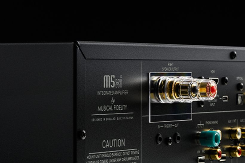 Vue détaillée de la face arrière de l'amplificateur intégré Musical Fidelity M5xi, montrant les borniers haut-parleurs plaqués or, les entrées HDMI eARC, optique TOSLINK, USB-C DAC, le sélecteur d'impédance phono MM/MC, les entrées RCA AUX et le logo officiel M5xi Integrated Amplifier by Musical Fidelity, designed in England built in Taiwan