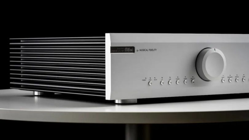 Amplificateur intégré Musical Fidelity M6xi en finition argent, avec large bouton de volume central et dissipateurs latéraux en aluminium extrudé, posé sur une table ronde