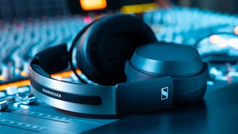 Casque studio fermé Sennheiser HD 480 PRO avec arceau aluminium brossé et coussinets cuir, posé sur une console de mixage en éclairage ambiant bleu et orange