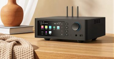 Lecteur réseau et DAC R2R Shanling SM1.3R noir avec écran tactile affichant des applications de streaming musical sur un bureau en bois.