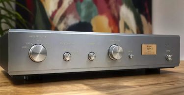 Préamplificateur à tubes Air Tight ATC-6 vu de trois-quarts face en finition argent champagne avec sélecteur Input Selector cinq positions, Mode Selector stéréo reverse mono, contrôle Balance, gros bouton de Volume Control central, sélecteur Mute et plaque dorée signature ATC-6 Stereo Preamplifier sur table en bois clair