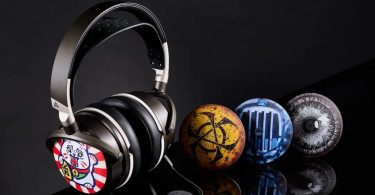 Casque Audeze Maxwell 2 en finition gris anthracite portant une coque ReSkin Kankan Koneko (chat japonais Maneki-neko sur fond rayé rouge et blanc), aux côtés de trois autres coques magnétiques alignées en réflexion sur surface noire laquée : Flux Warning Biohazard jaune, Planar Scan radiographie bleue du driver, et Panopticon All-Seeing Eye