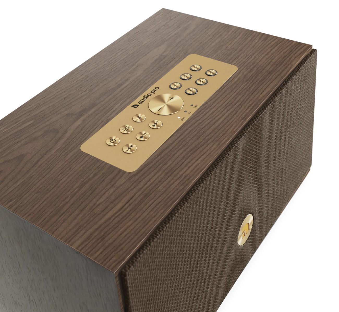 Vue détail macro de l'Audio Pro C5 MkII W en finition placage noyer véritable révélant l'harmonisation chromatique premium entre le grain naturel du bois noyer sur le dessus, le panneau de commande supérieur en métal laiton brass mat brossé avec logo audio pro gravé six boutons preset molette de volume rotative centrale avec marquages plus et moins six boutons fonctionnels et trois LED indicateurs WIFI BT LINE pour le mode source actif, et la grille frontale en tissu marron foncé chocolat avec bouton circulaire laiton brass central