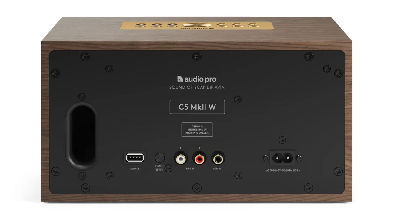 Vue arrière officielle de l'enceinte multiroom Audio Pro C5 MkII W en finition placage noyer véritable walnut veneer révélant la plaque arrière en métal noir mat avec marquages Design and Engineering by Audio Pro Sweden Sound of Scandinavia, évent de bass-reflex ovale noir à gauche, connectique complète port USB-A service bouton Connect Reset entrées RCA Line In stéréo sortie Sub Out pour caisson de basses et prise IEC alimentation universelle 100-240 volts, bordures en bois noyer apparentes