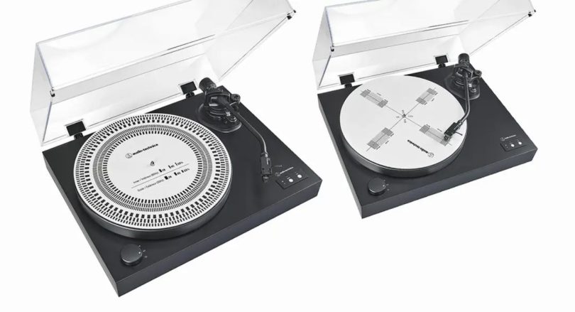 Vue marketing Audio-Technica AT-CAP4 montrant le disque deux-en-un sur deux platines vinyle noires capot transparent ouvert : à gauche la face alignement cellule avec graduations Baerwald, Stevenson, Löfgren B et UNI-DIN, à droite la face stroboscope blanche avec rectangles de calibration des vitesses 33, 45 et 78 RPM