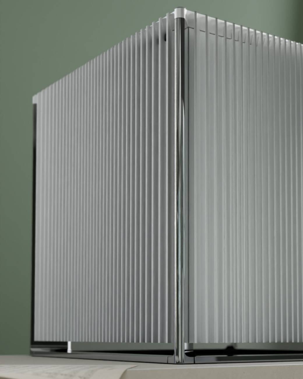 Gros plan sur l'angle du châssis de l'amplificateur Burmester 259, dévoilant les fines ailettes de dissipation verticales en aluminium argenté et l'arête chromée polie qui structure le coin du cube