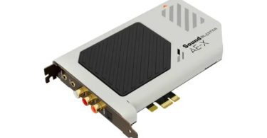 Carte son interne Creative Sound Blaster AE-X en finition blanche vue de trois-quart, montrant le dissipateur central hexagonal noir, le logo Sound Blaster AE-X, le connecteur PCIe 3.0 x1 et la connectique arrière avec jacks 3,5 mm, RCA L/R dorés et port optique TOSLINK