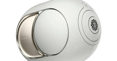 Enceinte connectée Devialet Phantom Ultimate en finition Light Pearl, vue de trois quarts montrant la forme sphérique signature, le woofer latéral à dôme ABS avec flasque PVD chromée et la grille du tweeter inspirée des jardins à la française du XVIIIe siècle, désormais compatible Qobuz Connect via la mise à jour DOS3