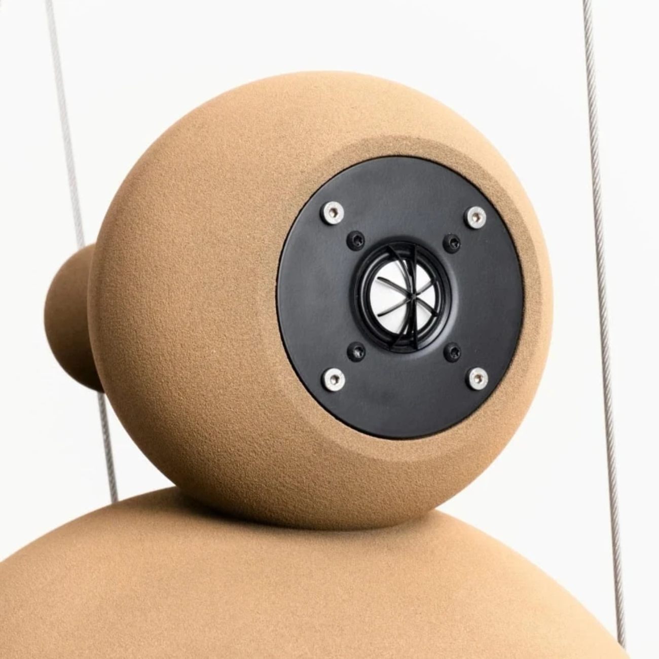 Détail macro du tweeter dôme magnesium-céramique de 28 mm Eton Audio monté sur la chambre sphérique supérieure de l'enceinte active Econik 1851, platine de fixation noire à 6 vis apparentes, texture minérale rugueuse caractéristique du sable de quartz imprimé 3D imprégné d'époxy en finition naturelle ton sable, câbles acier de suspension visibles en arrière-plan