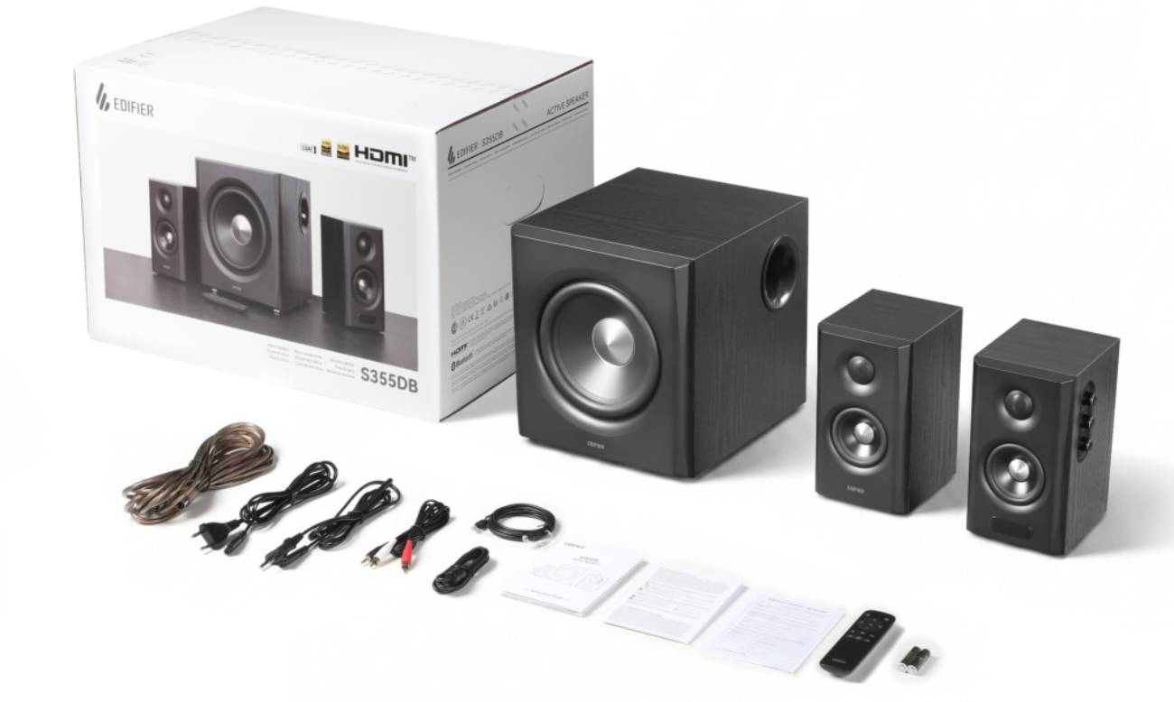 Vue de déballage du carton Edifier S355DB sur fond blanc, montrant le carton d'origine avec branding LDAC et HDMI, le subwoofer 8 pouces avec port bass-reflex arrière, les deux enceintes satellites finition bois noir, l'ensemble des câbles fournis (secteur, audio jack-RCA, optique, HDMI, liaison satellites), les manuels papier et la télécommande infrarouge