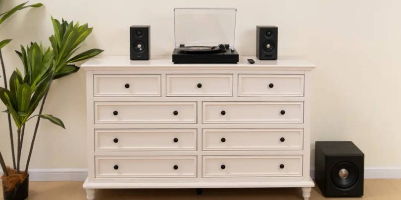 Système 2.1 Edifier S355DB en finition noire installé sur commode blanche avec deux enceintes satellites encadrant une platine vinyle, et subwoofer 8 pouces sans fil 5.8 GHz posé au sol à droite, dans un salon contemporain lumineux avec plante verte