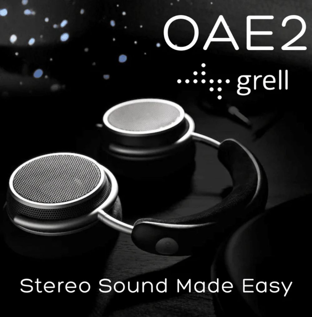 Visuel marketing officiel du casque Grell Audio OAE2 sur fond noir constellé de petits points bleus évoquant le cosmos, casque posé de biais avec ses deux écouteurs circulaires métalliques argentés à grille tissée fine, second transducteur secondaire plus petit visible en saillie sur la face avant de chaque écouteur caractéristique de la technologie FSFM, arceau souple en cuir noir matelassé, bras de jonction métallique argenté, logotype OAE2 en grandes capitales blanches et logo grell en haut à droite, slogan Stereo Sound Made Easy en bas
