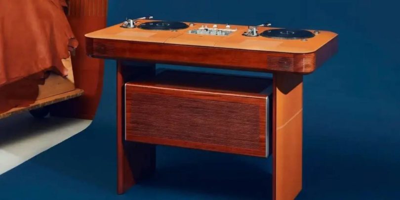 Table de DJ Hermès Atelier Horizons Disque Jockey Club en acajou verni, avec deux platines vinyle japonaises et une table de mixage centrale exposées sur le plateau, panneau frontal habillé de cuir, posée sur fond bleu dans un intérieur contemporain