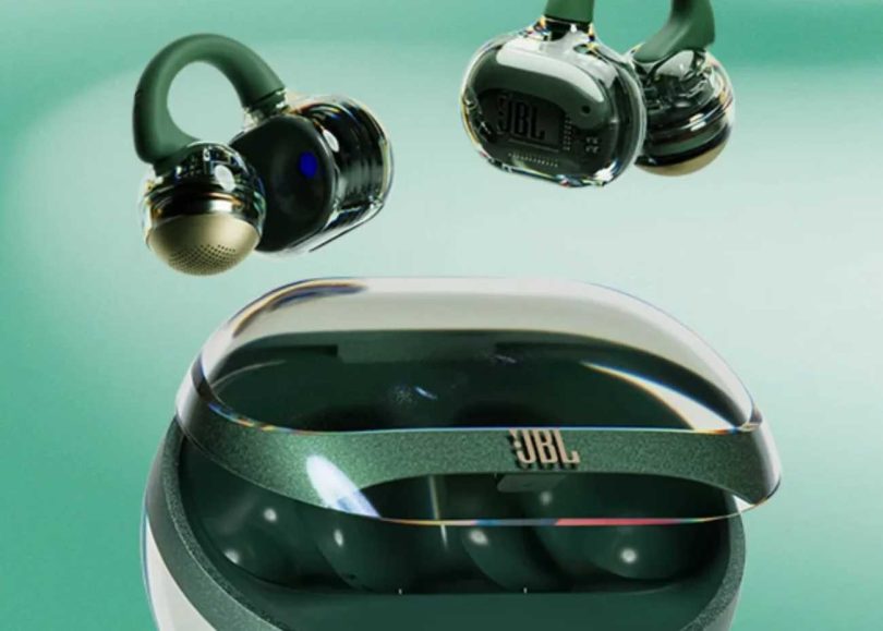 Paire d'écouteurs open-ear JBL Soundgear Clips en finition Emerald Green translucide, suspendus au-dessus de leur boîtier de charge vert émeraude, mettant en évidence le design SonicArc avec arc TPU flexible et driver dynamique 11 mm visible