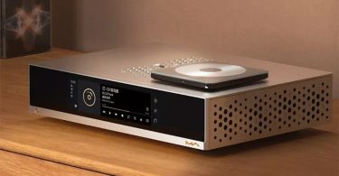 Streamer-DAC Matrix Audio MS-1c en chassis aluminium argent avec écran tactile en façade affichant la lecture d'un CD en PCM 44.1 kHz 16 bit, drive CD USB externe top-loader posé dessus, motif de trous d'aération circulaires sur le côté droit, posé sur table en bois clair