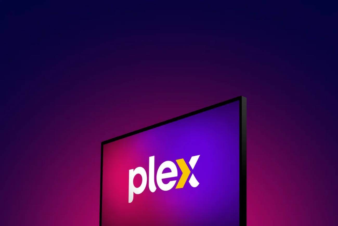 Écran de télévision affichant le logo Plex blanc avec le chevron orange caractéristique, sur fond dégradé violet et rose néon, illustrant l'annonce officielle de la hausse du Plex Pass à vie à 749,99 USD au 1er juillet 2026